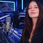 Betty Moon recording in a professional music studio with mixing consoles and audio equipment.